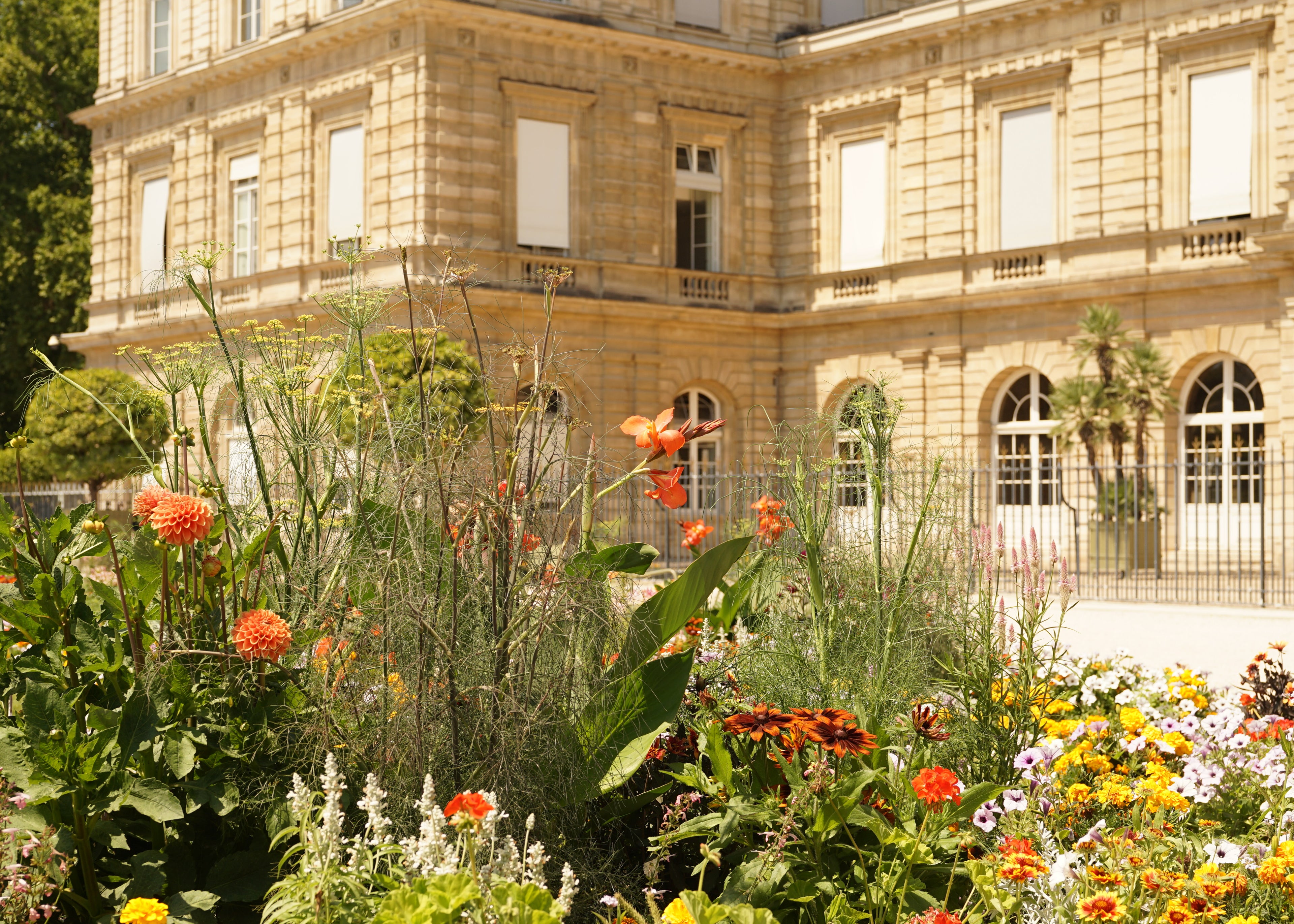 French floral garden in front of a large building with classical architecture