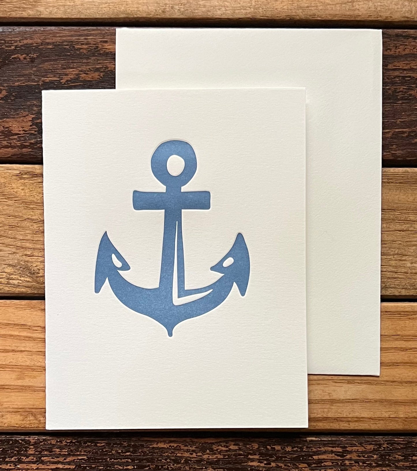Note card with blue anchor design on a wooden surface