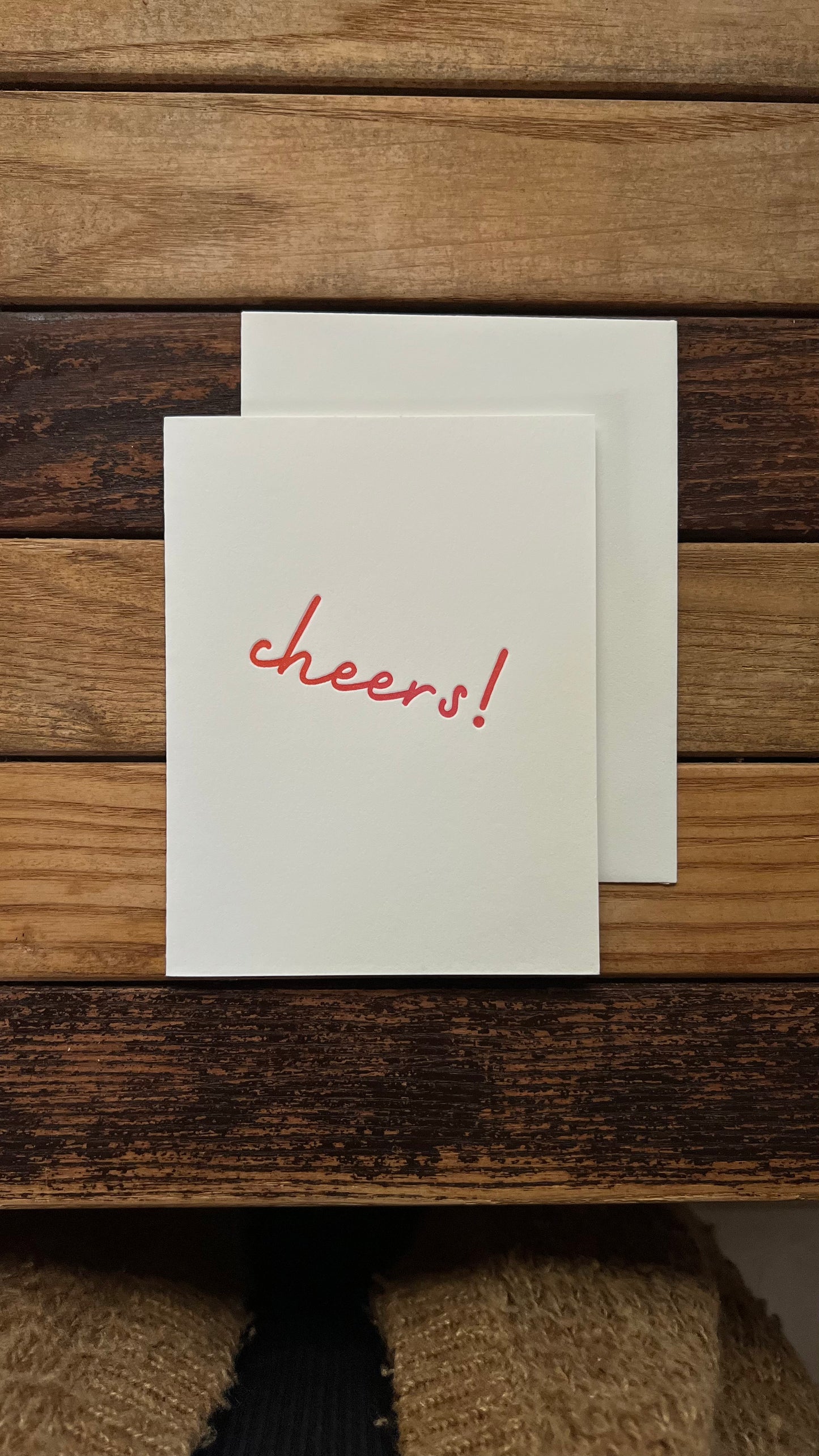 White card with 'cheers!' in orange on a wooden surface