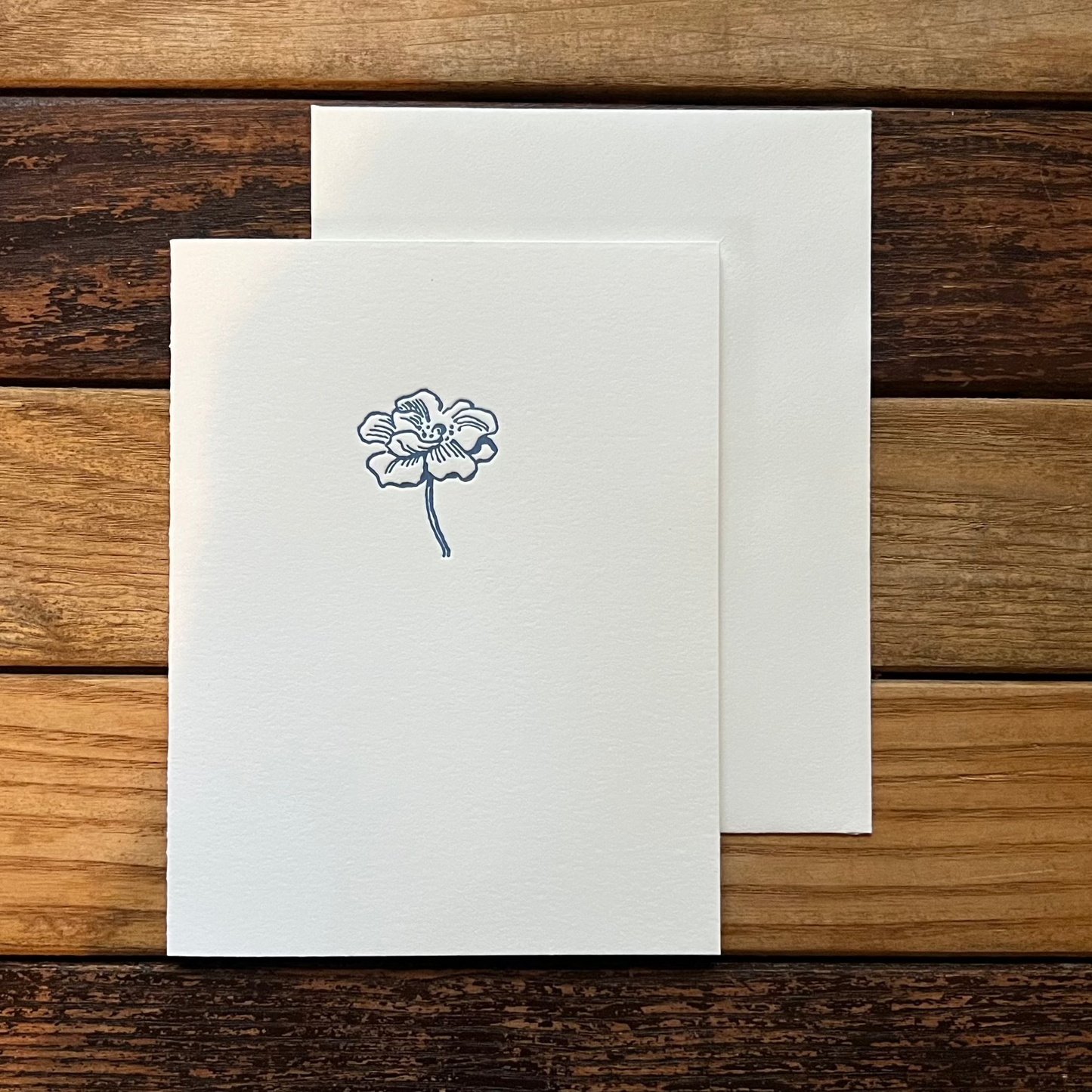Greeting card with a blue flower design on a wooden surface