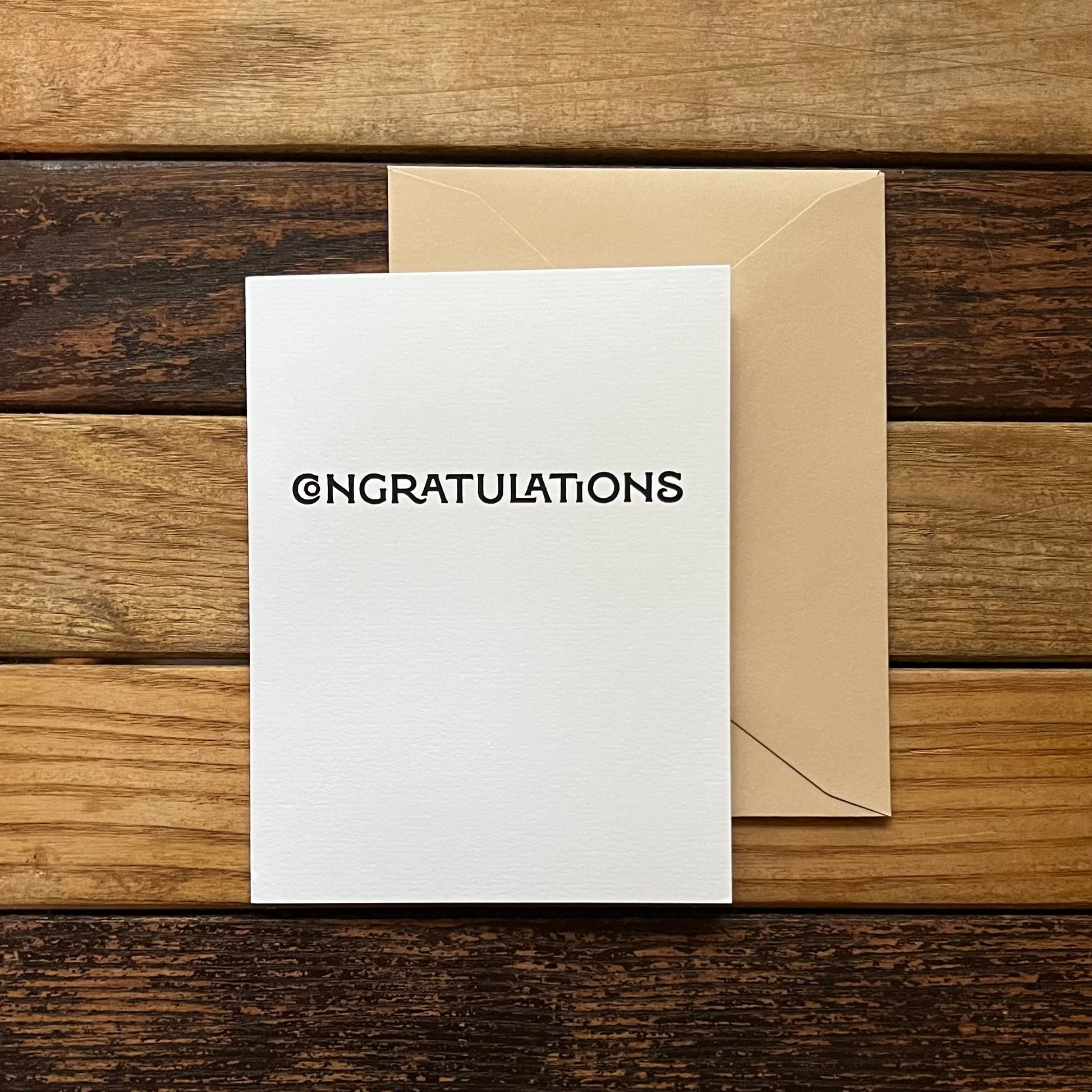 White card with 'CONGRATULATIONS' text on a wooden surface