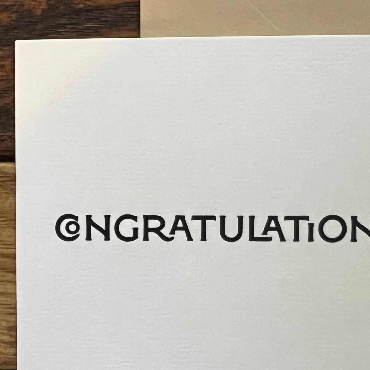 White card with 'CONGRATULATIONS' text on a wooden surface
