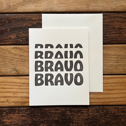 Card with 'BRAVO' text on a wooden surface
