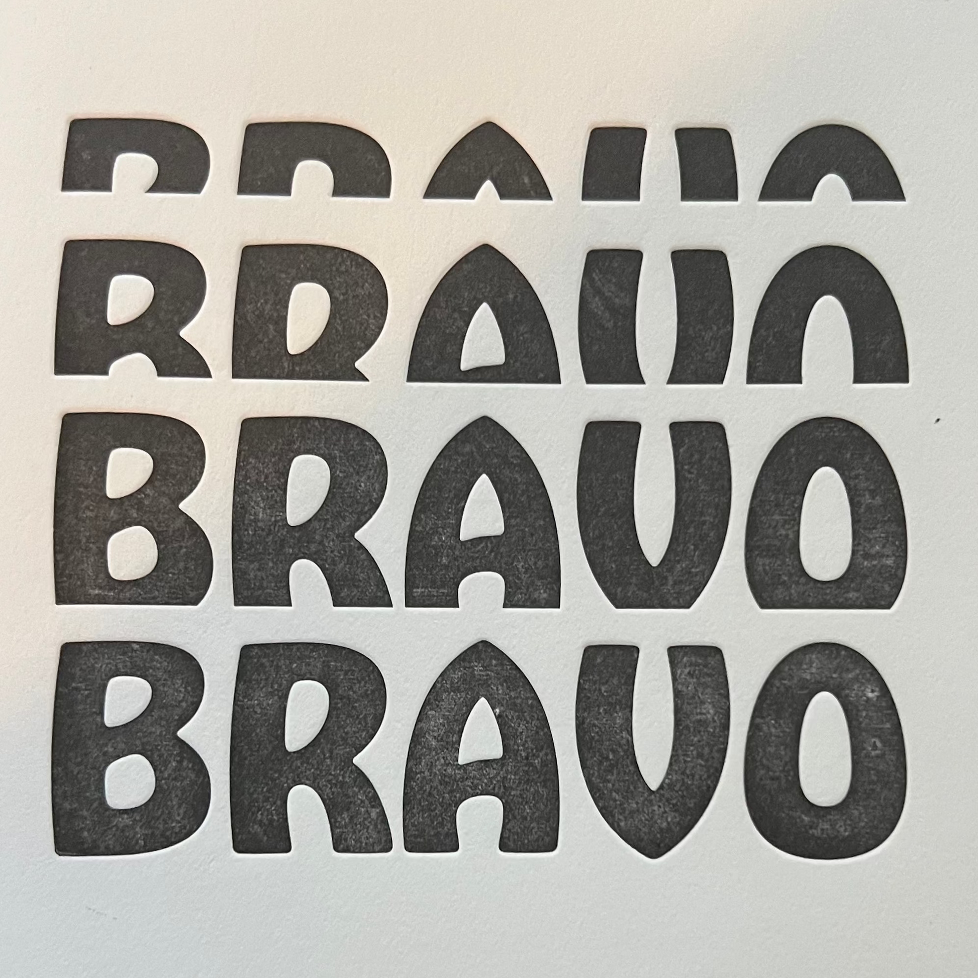 White card with 'BRAVO' text printed in black on a wooden surface