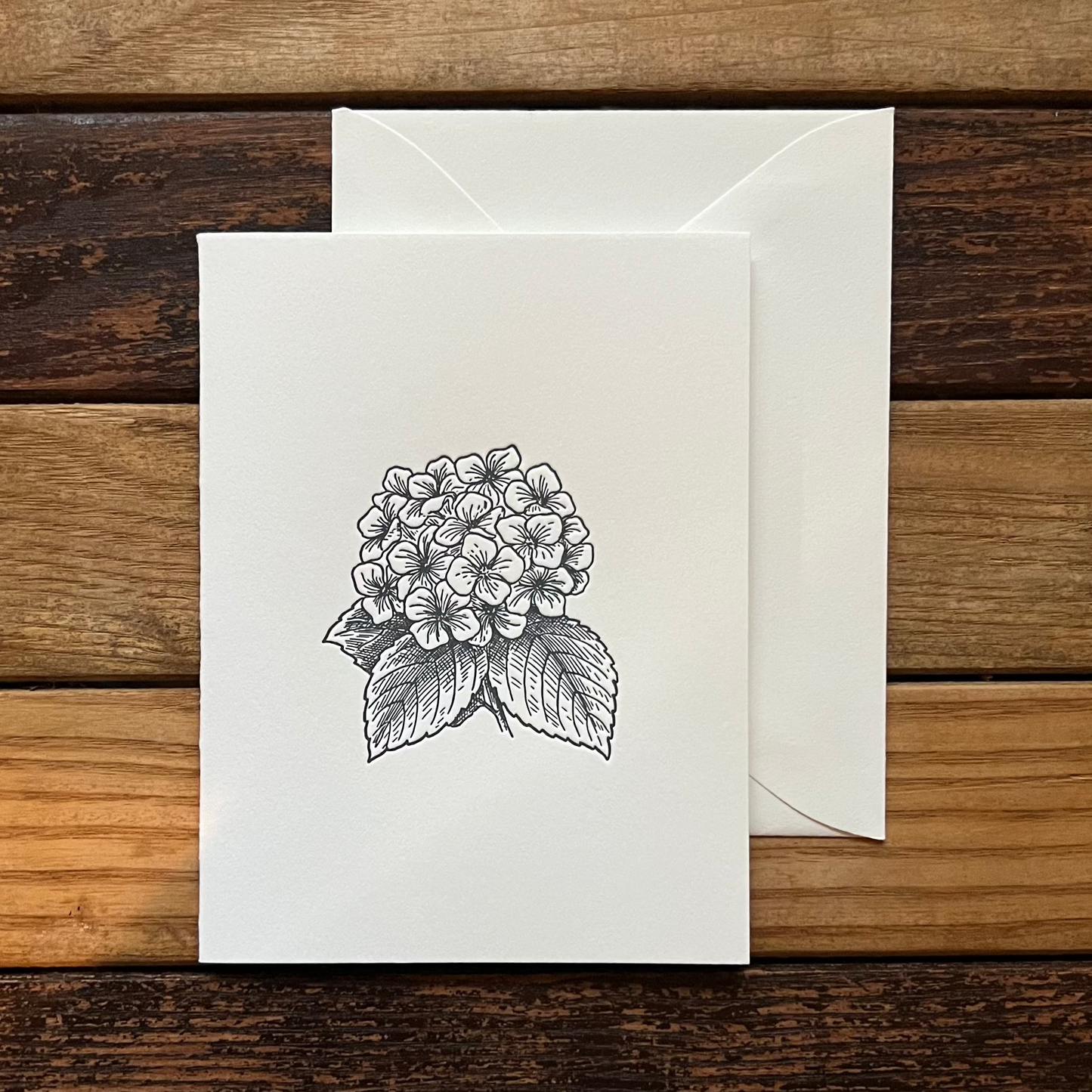 Greeting card with floral design and envelope on a wooden surface