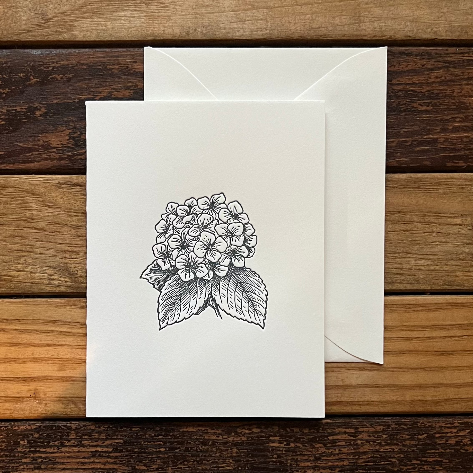 Greeting card with floral design and envelope on a wooden surface