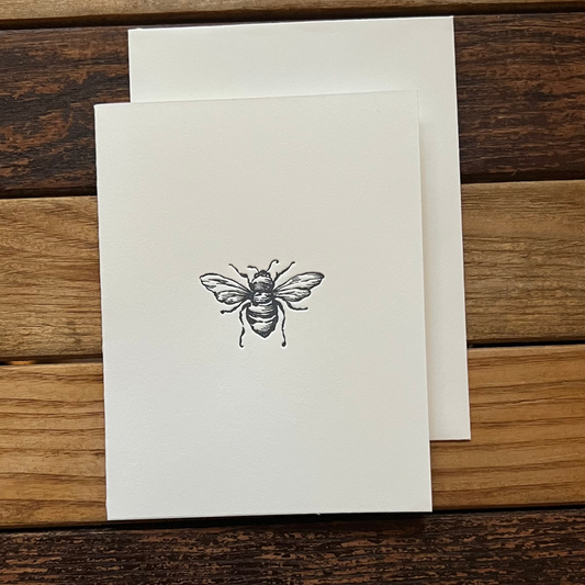 Card with a bee design on a wooden surface