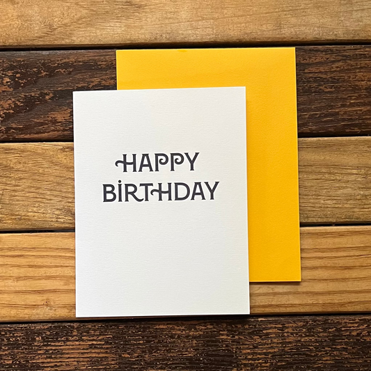 White card with 'Happy Birthday' text on a wooden surface