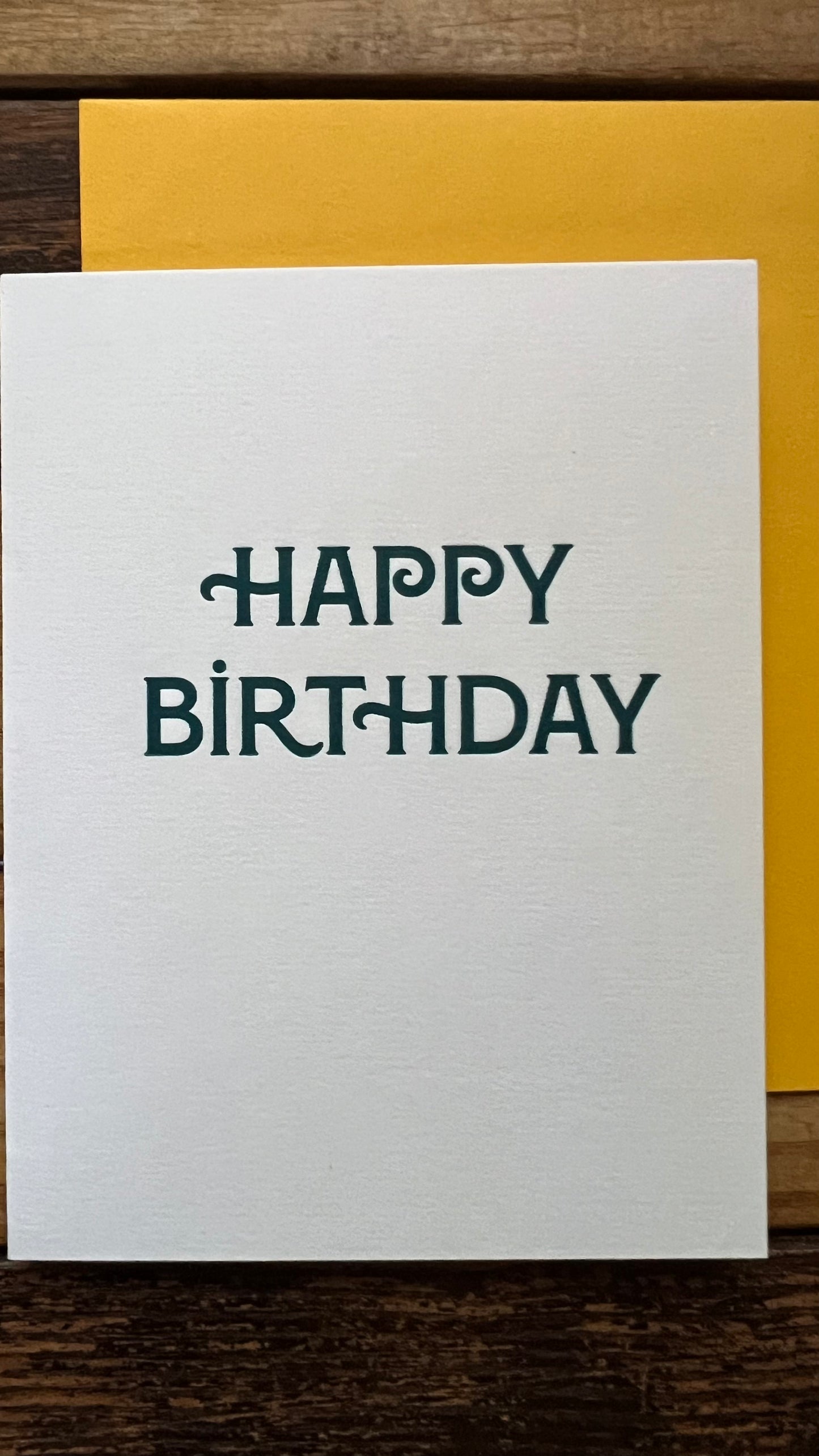 White card with 'Happy Birthday' text on a wooden surface