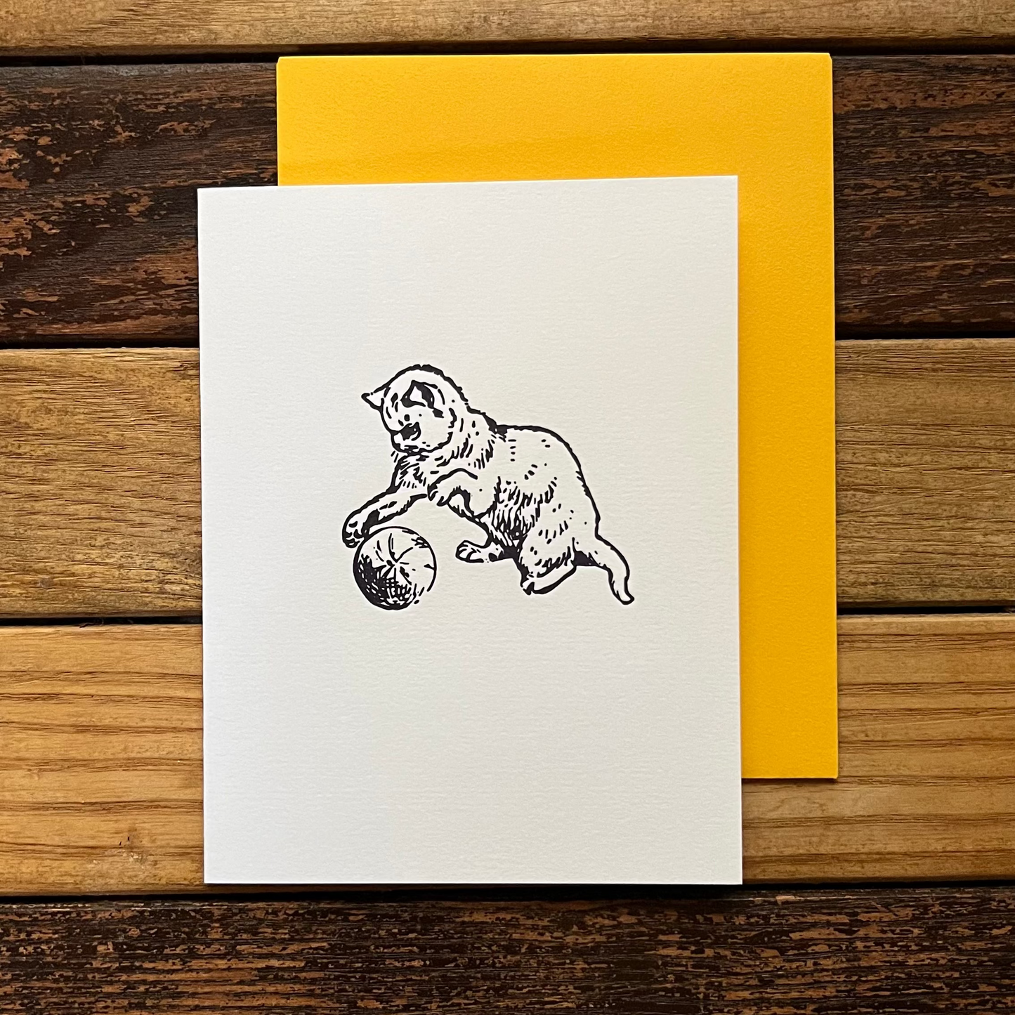 Greeting card with bear illustration on white paper, yellow envelope on wooden surface