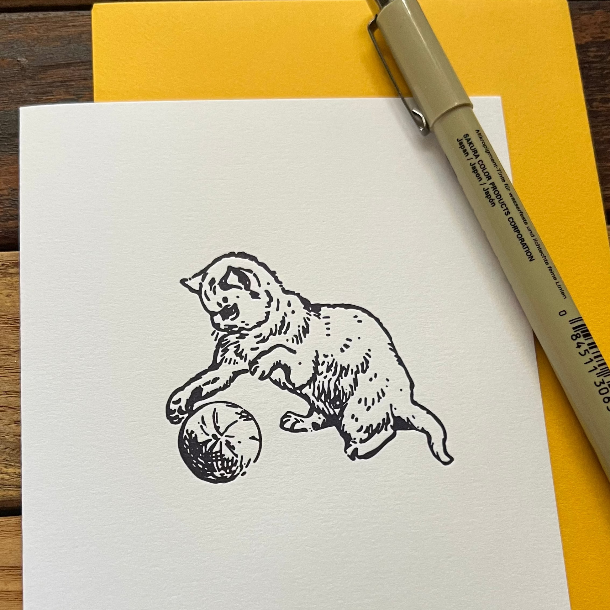 Notebook with a dog illustration on a wooden surface with a pen and yellow paper.