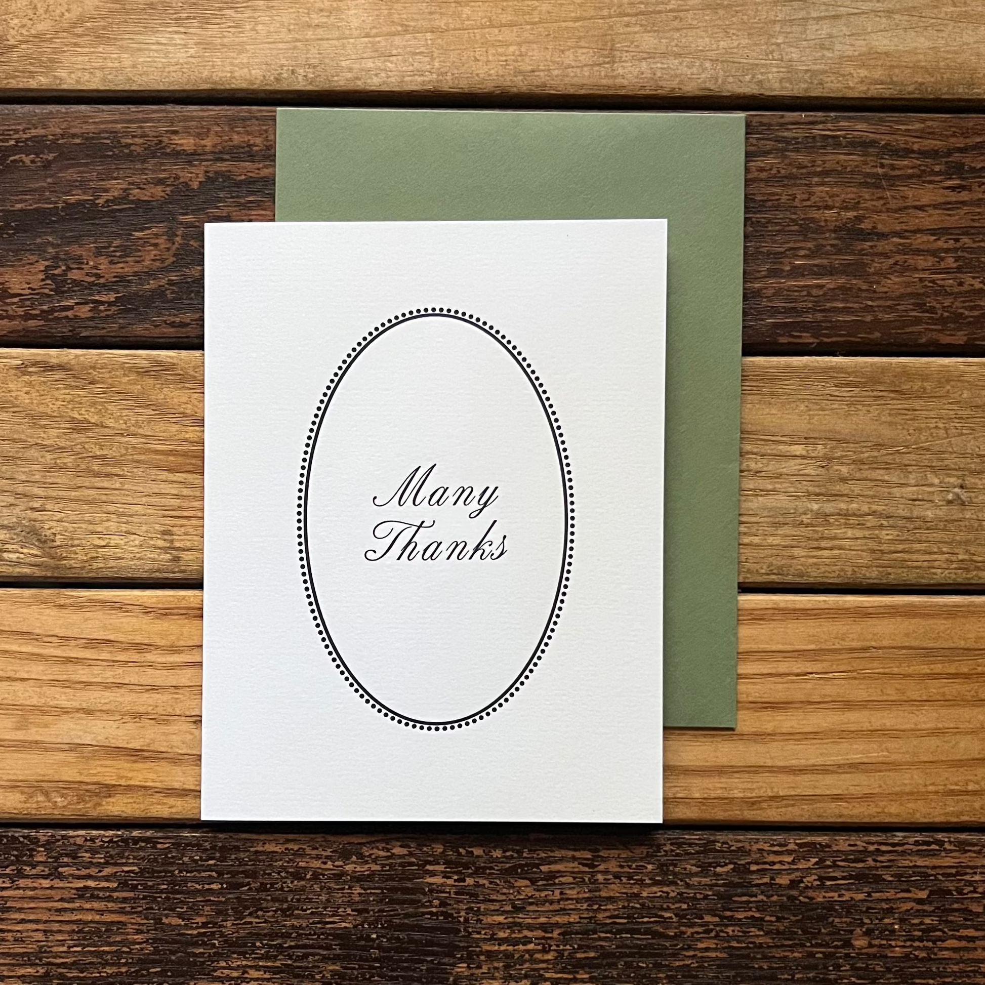 White card with 'Many Thanks' on a wooden surface