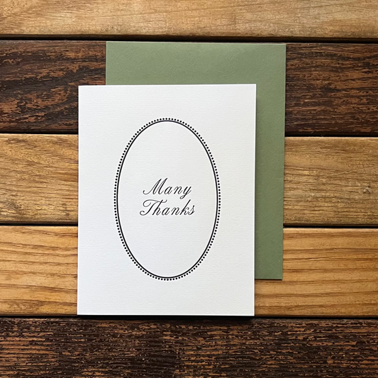White card with 'Many Thanks' on a wooden surface