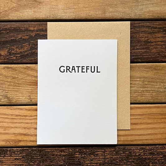 White card with 'GRATEFUL' text on a wooden surface