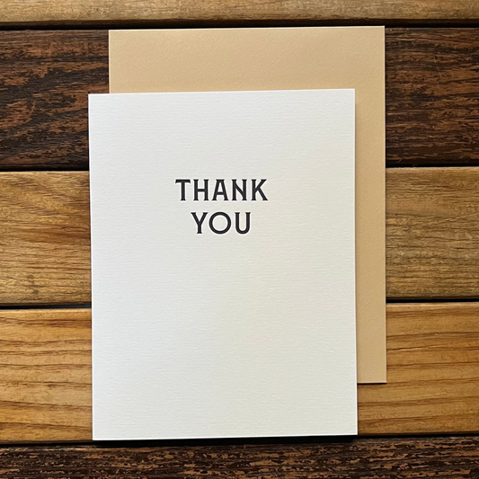 White card with 'THANK YOU' text on a wooden surface