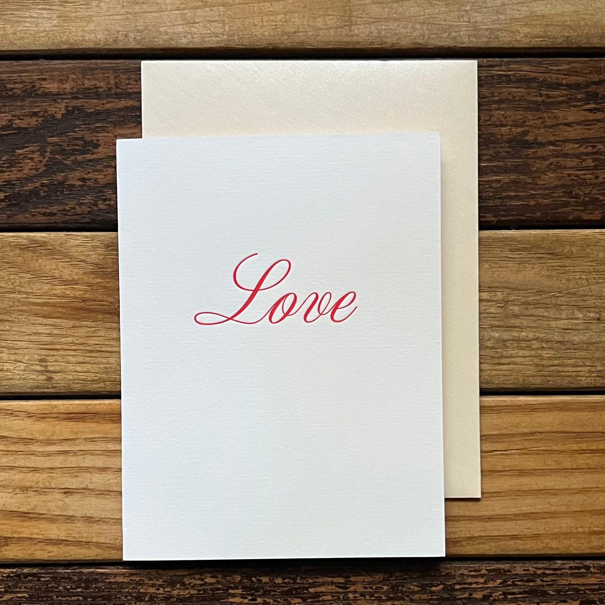 White card with 'Love' printed on it, placed on a wooden surface.