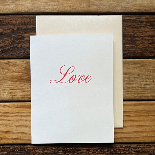 White card with 'Love' printed on it, placed on a wooden surface.